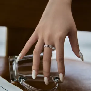 Détail d'une bague fleur ajourée en argent 925 portée au doigt dans un cadre chaleureux