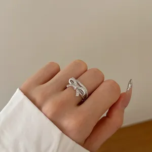Detailed close-up of a silver bow ring with white cubic zirconia on a female finger
