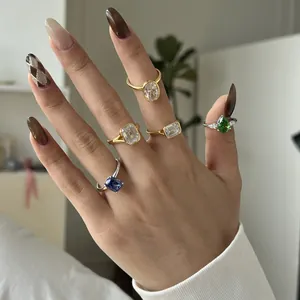 Detailed view of layered gemstone rings in emerald green and blue on a hand