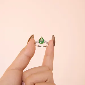 Macro detail of S925 silver ring featuring a pear-cut green gemstone with side stones