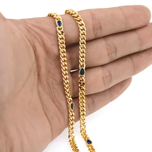 Détail d'une chaîne gourmette dorée 18K avec breloques gouttes bleues tenue en main