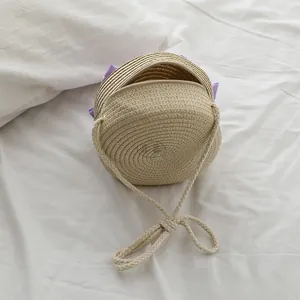 Vista dettagliata della borsa a tracolla rotonda in paglia con fiocco viola decorativo