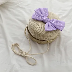 Dettaglio della borsa tonda in paglia con fiocco viola a pois e tracolla in corda