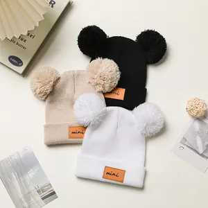 Detail van gebreide mutsen met dubbele pompons en een klein mini-leren label erop