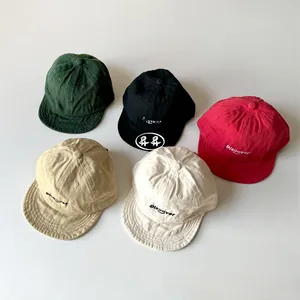 Flat lay of five cotton soft-brim baseball caps for kids in varied colors with embroidery