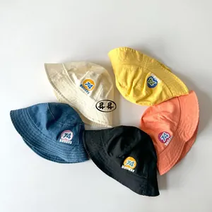 Flat lay of colorful cotton kids' bucket hats with 74 Holiday logos in five vibrant colors