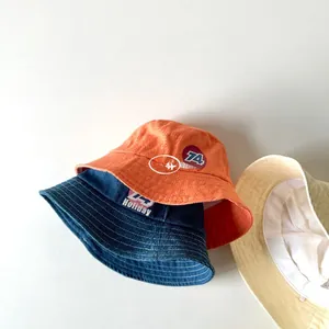 Detailed top view of canvas sun hats in orange, blue, and beige with 74 Holiday print