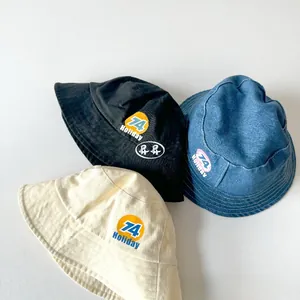 Three colors of kids bucket hats in black, denim blue and beige with badge detail