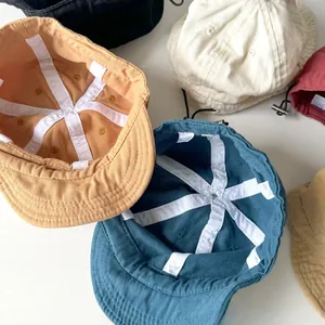 Top view of multi-colored cotton baseball caps with adjustable drawstrings on white surface