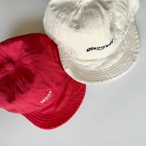 Detail of cotton twill kids baseball caps with discover embroidery in beige and red