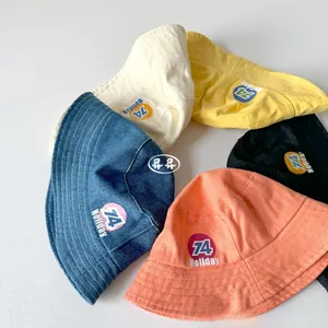 Detail view of cotton kids bucket hats in five colors with holiday 74 circle patch