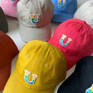 Détail de casquettes enfant avec broderie lettre U arc-en-ciel et toile de coton durable