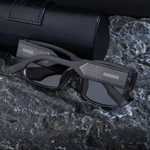 Detail of square polarized sunglasses with silver metal temples on grey rock texture