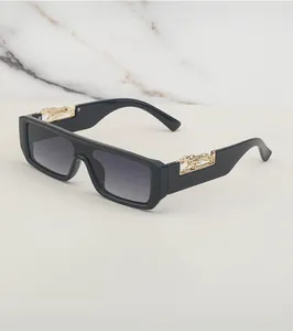 Detail van een zwarte rechthoekige zonnebril met goudkleurige cheetah metalen accenten