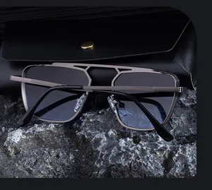 Détail des lunettes pilote carrées avec monture en métal et étui en cuir sur pierre sombre