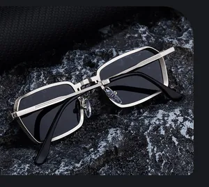 Detail view of silver metal sunglasses frame with grid texture on dark stone surface
