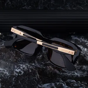 Detailed view of black square sunglasses with engraved gold metal temple accents