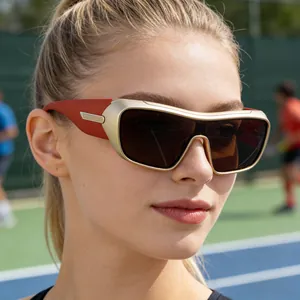 Close-up of futuristic sports sunglasses with gold frames and red temples on model