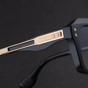 Detailed close-up of golden metal embossed hinge and rivets on black square sunglasses
