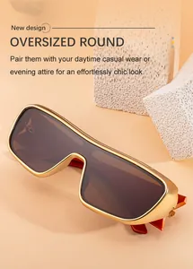 Detail of oversized gold metal sunglasses with brown shield lens on a stone prop