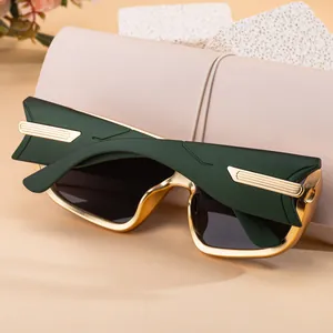Detailed close-up of dark green sunglasses with gold metallic accents and matte frame