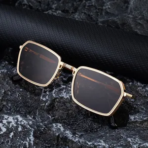 Retro square sunglasses with gold metal frame and dark lenses on a textured stone background