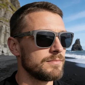 Detail of square polarized sunglasses with matte grey frames on model at a rocky beach