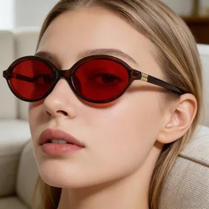 Macro detail of oval tortoiseshell sunglasses featuring red lenses and gold temple accents