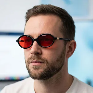 Detailed close-up of oval sunglasses with black frames and vibrant red lenses on a model