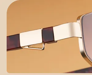 Detailed close-up of golden metal hinge and brown tortoiseshell texture on sunglasses