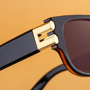 Close-up of square frame sunglasses featuring a golden B-shaped metal hinge and dark lenses