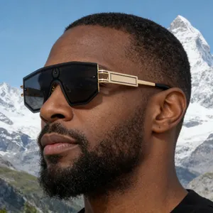 Detail of oversized shield sunglasses with gold textured temples against a snowy mountain