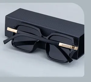 Détail de lunettes de soleil carrées avec charnière en métal doré et étui en cuir noir