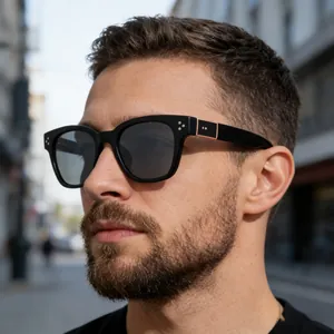 Close-up of black square sunglasses on model with silver rivets and gold temple detail
