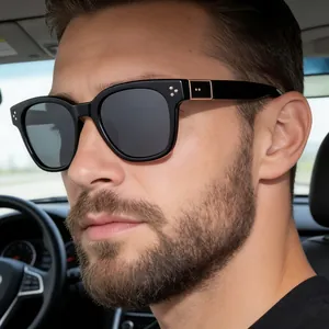Close-up of square sunglasses with gold metal accents and rivets worn in a luxury car