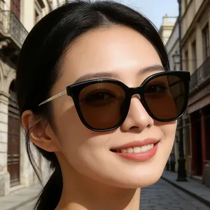Lunettes de soleil œil de chat à verres marron foncé et branches fines en métal doré sur modèle