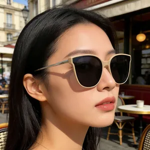Gros plan de lunettes de soleil œil-de-chat beige avec branches en métal doré portées dehors
