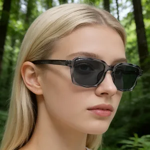 Nahaufnahme einer grauen transparenten eckigen Sonnenbrille vor natürlichem Waldhintergrund