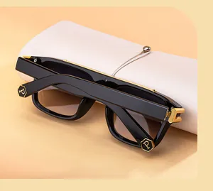 Detalle de gafas de sol negras con lentes degradadas y logo P hexagonal dorado en la patilla