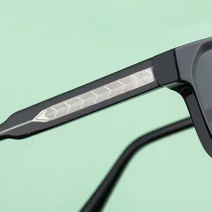 Macro detail of black square sunglasses temple with engraved silver metal core wire