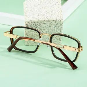 Detailed side view of square glasses with gold geometric cutout temples on stone