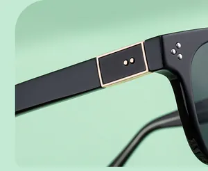 Close-up of black square sunglasses featuring gold metal accents and triple rivet details