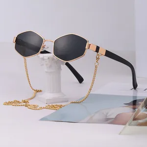 Chic hexagonal metal sunglasses with golden chain and black lenses on a stone pedestal