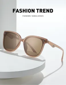 Detail of translucent brown oversized sunglasses featuring silver rivets on a white podium