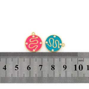Detailed macro view of 18K gold plated snake charms with enamel inlay and ruler for scale