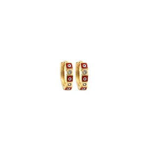 Detailed macro of gold hoop earrings with red enamel evil eye charms and clear zircons