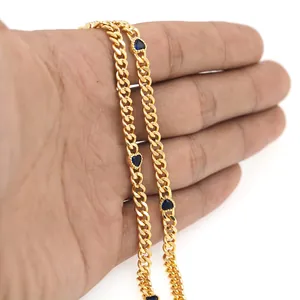 Detail einer goldenen flachen Kette mit herzförmigen blauen Edelsteinen in der Hand