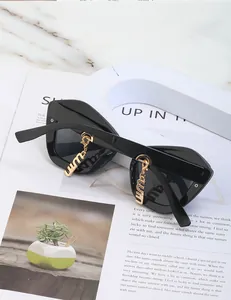Vue détaillée des lunettes de soleil œil-de-chat noires avec breloques dorées