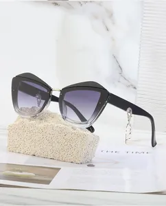Détail de lunettes de soleil œil-de-chat noires avec verres dégradés et pendentif doré