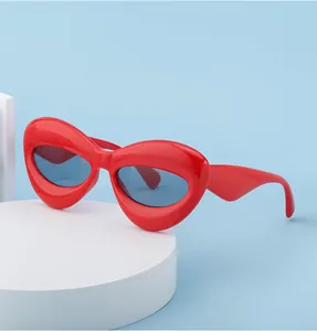 Detail of red oversized lip-shaped sunglasses on a minimalist display stand